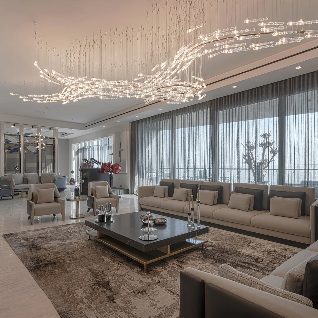 Wide living room at Tandis Zanbagh Residence in Zaferaniyeh, with full-height glazing, a sculptural crystal chandelier, pale stone flooring and tailored neutral seating.