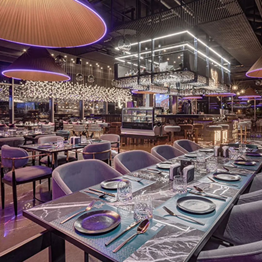 Dining room at View Lounge Restaurant in Aqdasiyeh, with patterned stone flooring, sculptural pendant lights and layered purple and brass details.